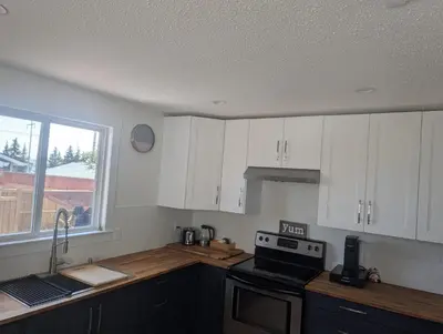 a kitchen with white cabinets and a stove and a window at A Little R and R Private Sauna Cold and Hot Plunge in Calgary