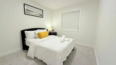 a white bedroom with two beds and a window at Casa Koko in Calgary