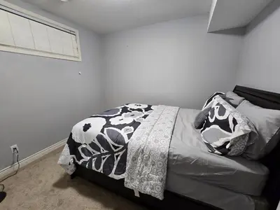a bedroom with a bed with a black and white blanket at Basement Suite Private Entry Fort McMurray in Fort McMurray