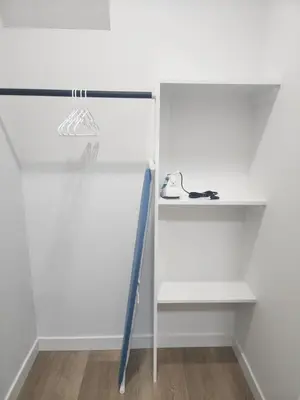 a white closet with a shelf and a baseball bat at Home in Calgary in Calgary
