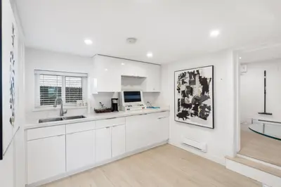 a white kitchen with white cabinets and a sink at Callister BNB in Vancouver