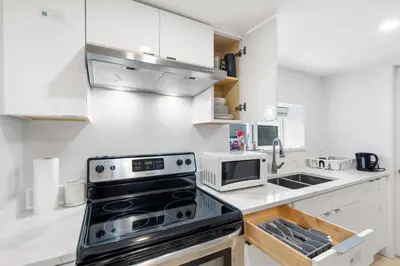 a kitchen with white cabinets and a stove top oven at Callister BNB in Vancouver