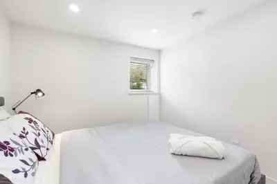 a white bedroom with a bed and a window at Callister BNB in Vancouver
