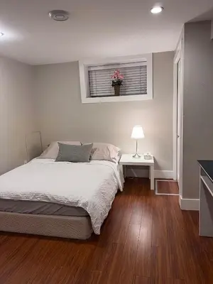 a bedroom with a bed and a table and a window at Vancouver Comfort Home 10 min to YVR airport, Close to Downtown in Vancouver