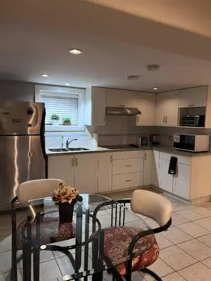 a kitchen with a glass table and chairs and a kitchen with white cabinets at Vancouver Comfort Home 10 min to YVR airport, Close to Downtown in Vancouver