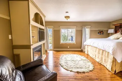 a bedroom with a bed and a couch and a fireplace at Elowen Suites Downtown in Drumheller
