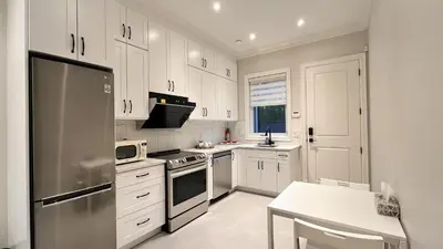 a kitchen with white cabinets and a stainless steel refrigerator at Vancouver Richmond Villa 41 in Richmond