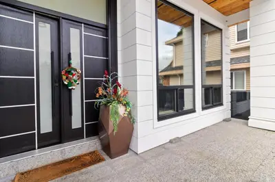 a porch with black doors and a potted plant at Spacious 6BR Entire Home Sleeps 14 Private Parking Pet-Friendly Near Vancouver in Surrey