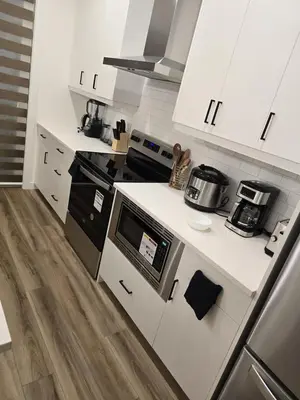 a kitchen with white cabinets and a stove top oven at Modern Comfort - With AC in Calgary