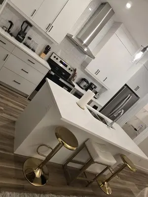 a kitchen with a white counter and gold stools at Modern Comfort - With AC in Calgary