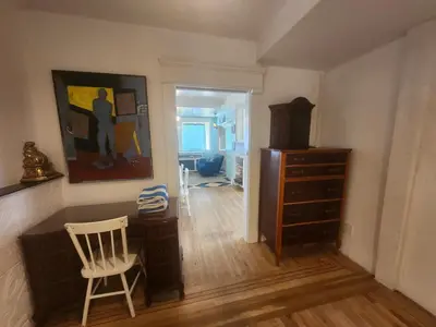 a room with a chair and a dresser and a painting at Lakeview Suite by Trout Lake in Vancouver