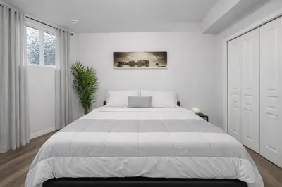 a white bedroom with a large bed and a window at Bright 2BR Suite Near YYC & Mall in Calgary