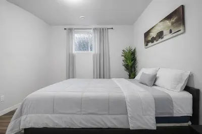 a bedroom with a large white bed with a window at Bright 2BR Suite Near YYC & Mall in Calgary