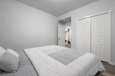 a white bedroom with a large bed and a closet at Bright 2BR Suite Near YYC & Mall in Calgary