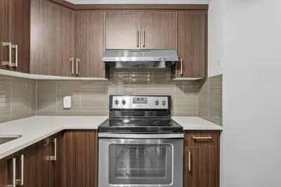 a kitchen with a stove and wooden cabinets at Large House with Billiards, 5 Bedrooms, Garage Parking & Free Banff Access in Calgary