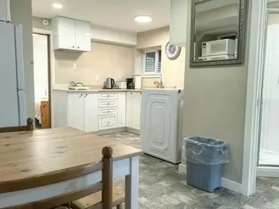 a kitchen with white cabinets and a wooden table at Private Cozy 2bdrm Sleep5pp Metrotown! Free Parking! Self Check-in! in Burnaby