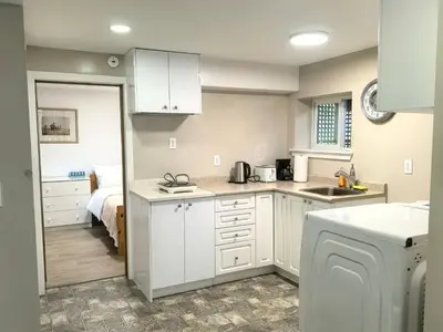 a kitchen with white cabinets and a bed in a room at Private Cozy 2bdrm Sleep5pp Metrotown! Free Parking! Self Check-in! in Burnaby
