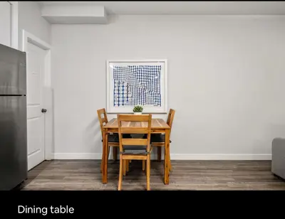 a dining table and chairs in a room at Brand new suite with parking pad at the back in Calgary