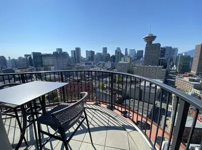 a table and chairs on a balcony with a view of a city at 3-Level Modern Luxury Sub-Penhouse, Best Ocean & City Views - Prime Downtown Location in Vancouver