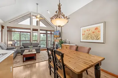a dining room and living room with a wooden table at 2BR in Nicklaus North, Mountain Views, Bright and Spacious, Tranquil Location in Whistler