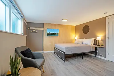 a bedroom with a bed and a chair and a table at The Rosemead Suite in Kelowna
