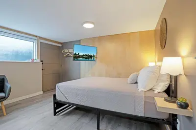 a bedroom with a bed and a tv on the wall at The Rosemead Suite in Kelowna