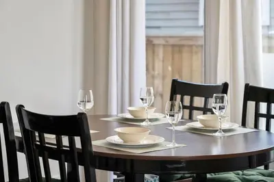 a wooden table with wine glasses and plates on it at Cozy Modern Pet Friendly Homes in Calgary