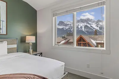 a bedroom with a large window with a mountain view at Amazing mountain Views 3BR Penthouse with private Balconies in Canmore