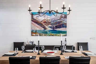 a dining room with a table with a painting on the wall at Sitka Spruce Mountain Chalet in Revelstoke