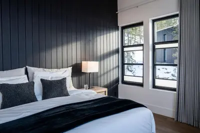 a bedroom with a large bed and two windows at Sitka Spruce Mountain Chalet in Revelstoke