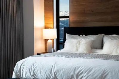 a bedroom with a large white bed with a window at Sitka Spruce Mountain Chalet in Revelstoke