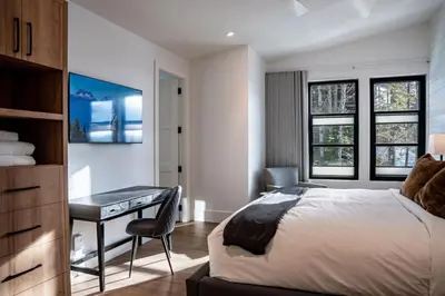 a bedroom with a bed and a desk and windows at Sitka Spruce Mountain Chalet in Revelstoke