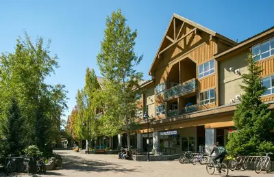 a person riding a bike in front of a building at 1BR and Den in Marketplace Lodge, Village Location, Mountain Views, Gas Fireplace, Parking in Whistler