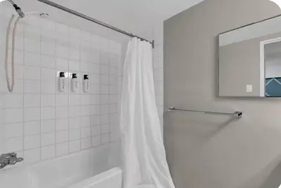 a bathroom with a shower with a white shower curtain at 17th Ave Cozy Nest in Downtown Calgary with Parking in Calgary