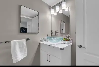 a white bathroom with a sink and a mirror at 17th Ave Cozy Nest in Downtown Calgary with Parking in Calgary