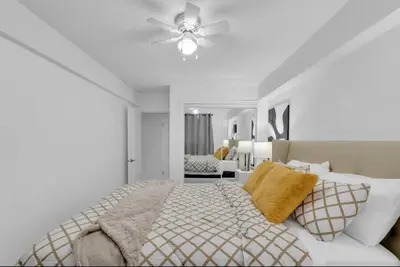 a white bedroom with a bed and a ceiling fan at 17th Ave Cozy Nest in Downtown Calgary with Parking in Calgary