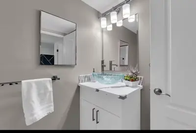 a white bathroom with a sink and a mirror at 17th Ave Cozy Nest in Downtown Calgary with Parking in Calgary