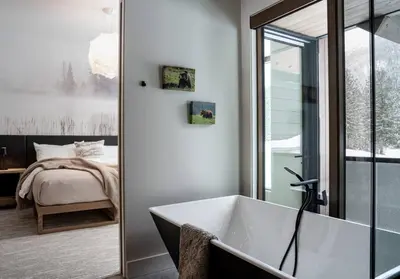 a bathroom with a bath tub and a bedroom at Mountain Lake Luxury Ski Chalet in Revelstoke