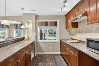 a large kitchen with wooden cabinets and a window at Luxury Home with 5 BR, 9 Beds, 4BA, sleep 12, AC, Crib in Calgary