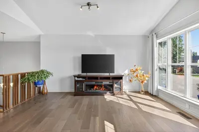 a living room with a flat screen tv and a fireplace at Luxury Home with 5 BR, 9 Beds, 4BA, sleep 12, AC, Crib in Calgary