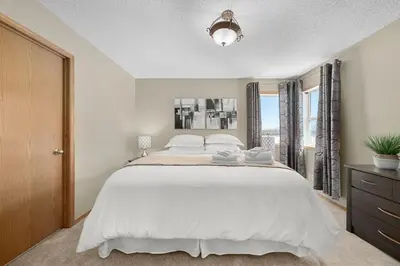 a bedroom with a large white bed and a window at Peacock Suites in Airdrie