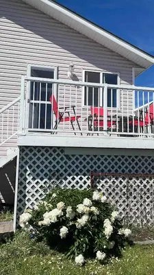 a house with a balcony with two chairs and flowers at Peacock Suites in Airdrie