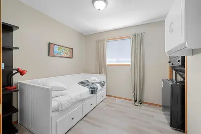 a bedroom with a white bed with a window at Peacock Suites in Airdrie