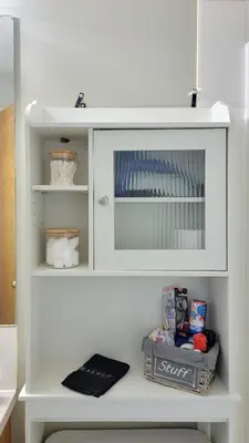 a white cabinet with a mirror in a bathroom at Peacock Suites in Airdrie