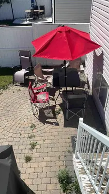 a group of chairs and a red umbrella on a patio at Peacock Suites in Airdrie