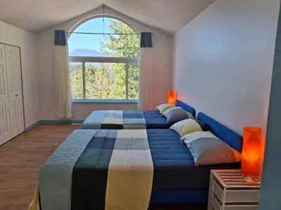 a bedroom with two beds and a large window at Blue Villa by the Sea in Sechelt