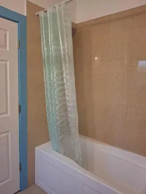 a bathroom with a tub with a clear shower curtain at Blue Villa by the Sea in Sechelt