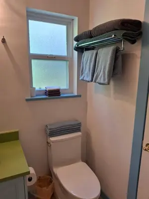 a bathroom with a toilet and a window and towels at Blue Villa by the Sea in Sechelt