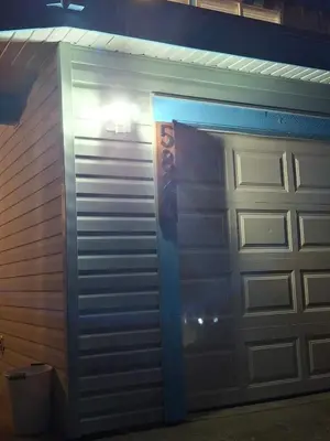 a garage with a metal garage door and a trash can at Blue Villa by the Sea in Sechelt