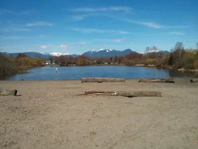 a beach with a lake and mountains in the background at Garden View double room suite at Trout Lake in Vancouver